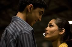 a man standing next to a woman with her face painted like a bird on her forehead