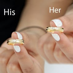 two hands holding gold wedding bands and one with white nails, both have their fingers in the same direction