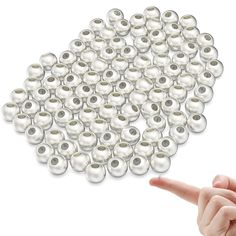 a hand pointing at a bunch of white pearls on a white background with one finger