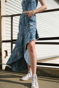 A distressed denim skirt with front closure and asymmetric hemline. Matching top FT1215 Details: Self : 78% Cotton 22% Polyester Size & Fit - Model is 5`9" And Wearing Size Small- Measurements Taken From Size Small- Approx. length: Left 17 3/4"; Right 39 3/4" Asymmetrical Hem Denim Skirt In Medium Wash, Asymmetrical Medium Wash Bottoms For Summer, Denim Blue Asymmetrical Skirt For Summer, Denim Blue Skirt With Asymmetrical Hem For Summer, Asymmetrical Fitted Denim Skirt For Spring, Denim Blue Bottoms With Asymmetrical Hem For Summer, Dark Wash Bottoms With Asymmetrical Hem For Summer, Asymmetrical Cotton Denim Skirt, Asymmetrical Fitted Denim Skirt