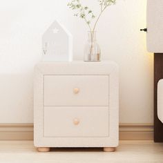 a white night stand with two drawers and a vase filled with baby's breath flowers