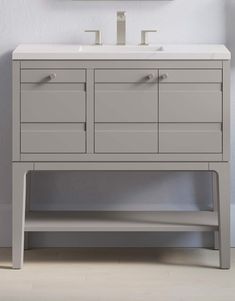 a white sink sitting under a mirror next to a wooden cabinet with two faucets