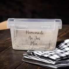 a plastic container sitting on top of a wooden table next to cloths and napkins