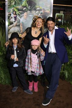 two adults and three children posing in front of a movie poster