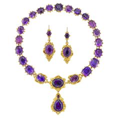 A late Georgian amethyst suite, the necklace centrally set with three oval faceted amethysts within gold scroll decorations, suspending a detachable drop with a pear-shaped and a small oval amethyst on a similar surround, attached to nineteen cushion and oval-cut faceted amethysts all set in closed-back collets, with a hidden snap clasp, accompanied by drop earrings of matching design, with gold wire fitting, all mounted in yellow gold, circa 1830, the necklace measuring approximately 41 x 6.3cm Luxury Victorian Amethyst Necklace, Luxury Heirloom Purple Necklace, Luxury Victorian Purple Jewelry, Luxury Antique Gemstone Jewelry, Luxury Purple Heirloom Necklace, Luxury Collectible Amethyst Jewelry, Luxury Exquisite Purple Jewelry, Luxury Amethyst Jewelry For Evening, Luxury Ornate Purple Jewelry