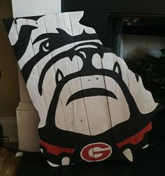 a wooden sign with a dog's face painted on it, sitting in front of a fireplace