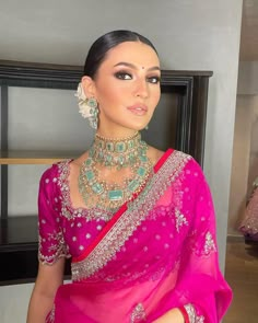 a woman wearing a pink sari and jewelry