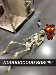 a skeleton laying on the floor next to a sign that says nooooooooo boo