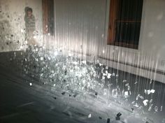 shattered glass on the ground in front of a window with a person standing behind it