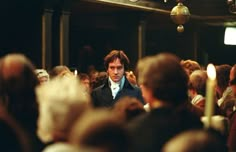 a man standing in front of a crowd of people with candles on each side of his face