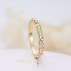 a close up view of a gold ring with diamonds on it's sides, sitting on a white surface