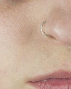 a woman's nose with an ear piercing in the shape of a crescent on her left side