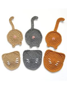 four crocheted cats with different colors and designs on them, one is orange, the other is gray