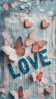 some pink and blue butterflies on top of a piece of paper with the word love spelled out