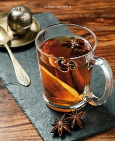 a glass cup filled with tea next to a spoon