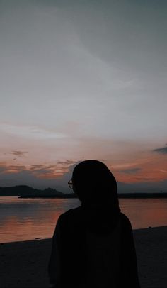 a person standing on the beach at sunset