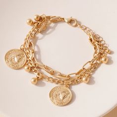 Layered chain bracelet with coin charms and ball charms. Approx Circumference: 8" + 2" extension Coin Charm Bracelet, Layered Chain, Layered Chains, Brass Gold, Chain Bracelet, Gold Bracelet, Coin, Gold Plate, Charms