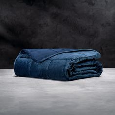 a dark blue blanket folded on top of a wooden table next to a black wall