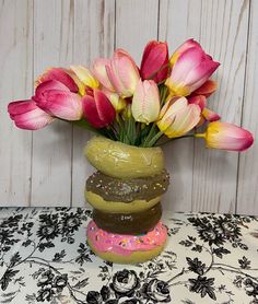 a vase filled with pink and yellow tulips on top of a white table