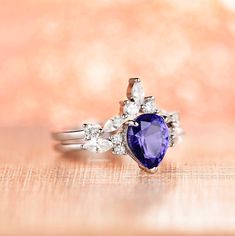 Gorgeous Vintage Inspired Tanzanite Ring Set►Made of 925 solid sterling silver with rhodium finish ►Accented with simulated diamonds (CZ)►Average band width: 1.7 mm►Sold as a setCenter Stone: Tanzanite Shape: Teardrop/ PearGem size: 7 x 9 mmCarat Weight: 1.7 ct. (approx.)Gemstone Creation: Simulated Hardness: 8 (Mohs scale)✓ 100% Nickel-Free✓ Hypoallergenic✓ Comfort Fit✓ Free Ring Box✓ Free USA Shipping Tanzanite Engagement Ring, Mohs Scale, Tanzanite Ring, Fine Jewelry Collection, Anniversary Gift For Her, Ring Box, Engagement Ring Settings, Custom Rings, Promise Rings