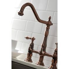 a faucet in a kitchen with white tiles on the wall and brown fixtures