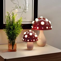 two mushroom lamps sitting on top of a table next to a potted plant