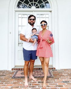 a man and woman standing in front of a white door with a baby on her lap