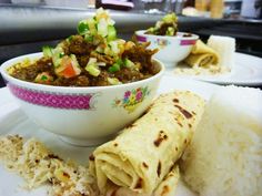 a plate topped with burritos and a bowl filled with food