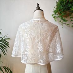 a mannequin is standing next to a plant and wearing a white lace top