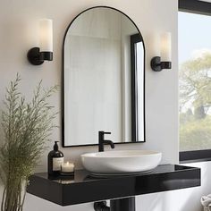 a bathroom sink sitting under a mirror next to a vase with a plant in it