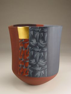 a vase with an orange and grey design on the outside, sitting on a white surface