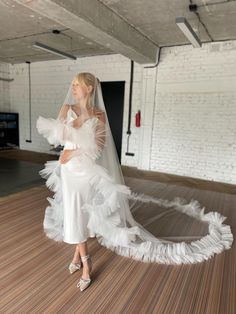 a woman in a white wedding dress is standing on the floor with her veil over her head