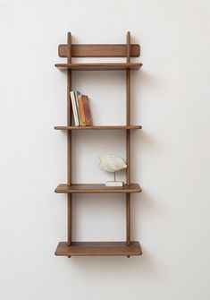 a wooden shelf with books on it against a white wall