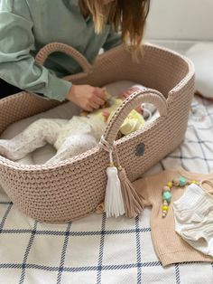 a woman holding a baby in a crocheted bassinet