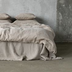 a bed with two pillows on top of it and a blanket over the headboard