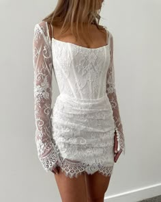 the back of a woman's white dress with long sleeves and lace on it