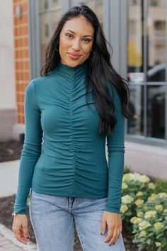 Elevate your style with this Green Cinched Mock Neck Top, which is also available in Red! Designed with long sleeves and a mock neckline, this top offers a sleek and polished look. The cinched front detail creates a flattering, gathered effect that enhances the fitted silhouette. Its versatile design makes it easy to dress up or down, whether paired with high-waisted jeans or a skirt for a night out. Ruched Long Sleeve Top For Fall, Fall Ruched Tops For Layering, Ruched Tops For Layering In Fall, Ruched Trendy Top For Fall, Fall Ruched Crew Neck Top, Ruched Fitted Long Sleeve Top For Fall, Casual Ruched Tops For Fall, Fitted Ruched Tops For Winter, Winter Ruched Fitted Tops