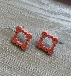 two pairs of pink earrings sitting on top of a wooden table