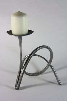 a white candle sitting on top of a metal stand