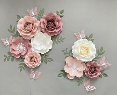 some paper flowers and butterflies on a gray background with white, pink, and grey leaves