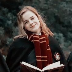 a girl wearing a harry potter scarf and holding an open book