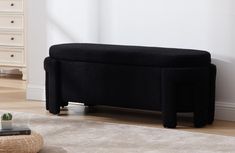 a black bench sitting on top of a white rug next to a dresser and drawers