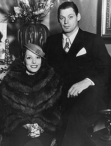 an old black and white photo of a man and woman sitting next to each other