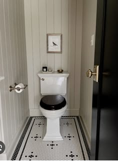 a white toilet sitting in a bathroom next to a black and white tile flooring