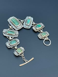 This is a rustic, handmade bracelet featuring mint green kyanite stones. Each piece was textured with silver dust, and each stone set in sterling silver. Each stone has hand stamped accents on either end providing more texture and design. The green makes a lovely contrast with the silver and granule-type texturing on the silver. The texture and shapes lend to the rustic feel of this piece and also contrast very beautifully with the deep clear green of the stones. It is a one of a kind piece and Luxury Artisan Faceted Jewelry, Green Patina Bracelet, Rustic Green Jewelry With Patina, Unique Green Sterling Silver Bracelets, Artisan Green Bracelet With Patina, Green Artisan Bracelet With Patina, Artisan Green Patina Bracelets, Rustic Silver Bracelet Jewelry, Unique Green Sterling Silver Bracelet