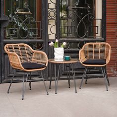 two wicker chairs sitting next to each other in front of a building with wrought iron doors