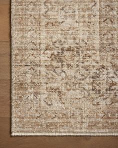 an area rug on top of a wooden floor with a brown and white color scheme