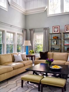 a living room with two couches and a coffee table in front of the windows