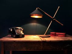 an old fashioned telephone sitting on top of a wooden desk next to a lamp and books