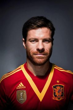 a man with a beard wearing a red and yellow soccer jersey looking at the camera